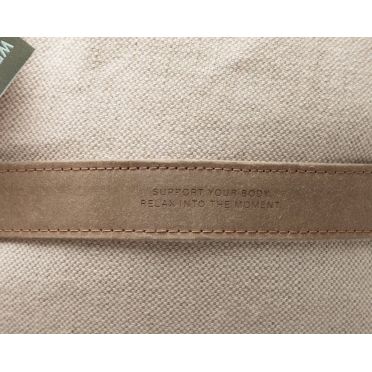 Zbliżenie na detal rączki wałka do jogi w kolorze ecru z wytłoczonym napisem „SUPPORT YOUR BODY, RELAX INTO THE MOMENT” oraz metką marki WELLB.